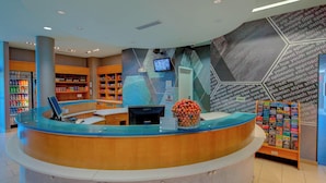 A reception area with a curved counter, a digital screen, and a wall with hexagonal patterns. - SpringHill Suites by Marriott Macon (Macon)