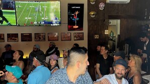 A bar with multiple TVs displaying sports games, a poster of a dance competition, and a variety of framed pictures on the wall. - Hotel Ana Catalina & Suites (San Miguel de Allende)