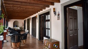 A covered outdoor seating area with wooden beams, a tiled floor, and a door leading to another room. - Hotel Ana Catalina & Suites (San Miguel de Allende)