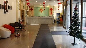 Een moderne lobby met een receptiebalie, een zithoek en een kerstboom.
