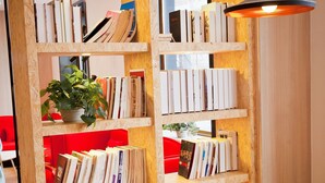 A modern library with wooden bookshelves, a red couch, and a hanging light fixture. - Ibis Harbin Hongqi Street Hotel (Harbin)