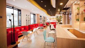 A modern interior with red seating, a bar area, and a large window providing a view of the outside. - Ibis Harbin Hongqi Street Hotel (Harbin)