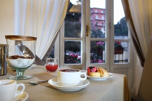 A table with a cup of coffee, a glass of red drink, and pastries.