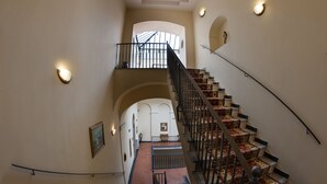A grand staircase with ornate railings and patterned carpet, leading to an upper level with a view of the outdoors. - Grand Hotel Capodimonte (Naples)