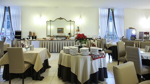 A dining area with tables set for service, a buffet line, and a large mirror on the wall. - Grand Hotel Capodimonte (Naples)
