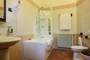 A bathroom with a bathtub, a sink, a toilet, a towel rack, and a hairdryer on the wall.