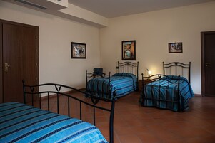 Una camera da letto con due letti, una porta in legno e un pavimento piastrellato.