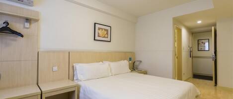 Ein Hotelzimmer mit Bett, Nachttischen, einem Kleiderschrank und einer Tür zu einem weiteren Raum.