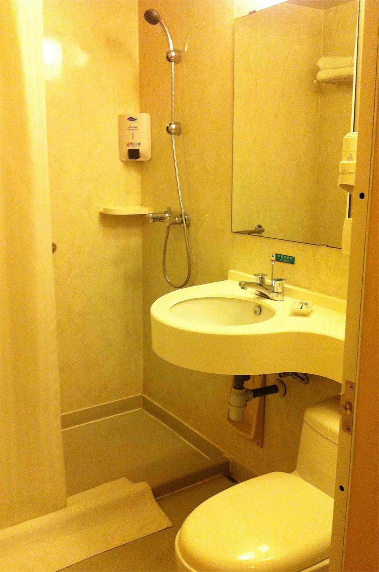 A small bathroom with a toilet, sink, and shower.