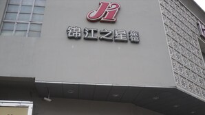 Ein Gebäude mit einem gut sichtbaren 'J'-Logo und chinesischen Schriftzeichen über dem Eingang.