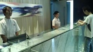 Ein Empfangsbereich mit einer Glastheke, einer Uhr an der Wand und einem Poster im Hintergrund.