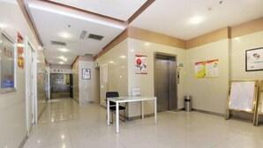 A clean, well-lit hallway with a reception desk, a trash bin, and informational posters on the walls. - Jinjiang Inn (Shenyang Middle Street Metro Station, Imperial Palace) (Shenyang)