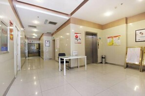 A clean, well-lit hallway with a reception desk, a trash bin, and informational posters on the walls. - Jinjiang Inn (Shenyang Middle Street Metro Station, Imperial Palace) (Shenyang)