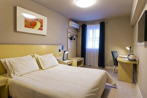 A hotel room with a bed, a desk, a chair, a nightstand, a lamp, a picture on the wall, and a window with curtains. - Jinjiang Inn (Shenyang Middle Street Metro Station, Imperial Palace) (Shenyang)