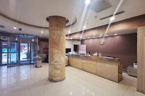 A hotel reception area with a marble column, a reception desk, and a clock on the wall. - Jinjiang Inn (Shenyang Middle Street Metro Station, Imperial Palace) (Shenyang)