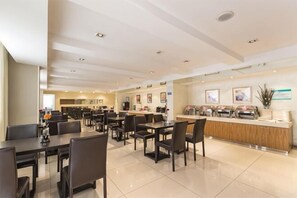 A spacious hotel dining area with multiple tables and chairs, a reception desk, and a kitchen in the background. - Jinjiang Inn (Shenyang Middle Street Metro Station, Imperial Palace) (Shenyang)