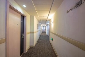 A hotel corridor with doors, a carpeted floor, and a sign on the wall. - Jinjiang Inn (Shenyang Middle Street Metro Station, Imperial Palace) (Shenyang)