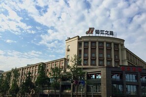 A multi-story building with a curved corner, featuring a prominent sign with Chinese characters. - Magnotel Chengdu Taikoo Li Dong Feng Bridge (Chengdu)