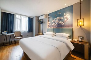 A hotel room with a bed, a desk, a chair, a painting on the wall, and a nightstand with a lamp. - Jinjiang Inn Chongqing Shopping & Entertainment (Chongqing)