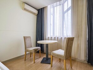 A room with two chairs, a round table, a window with sheer curtains, and an air conditioning unit on the wall. - Jinjiang Inn Chongqing Shopping & Entertainment (Chongqing)