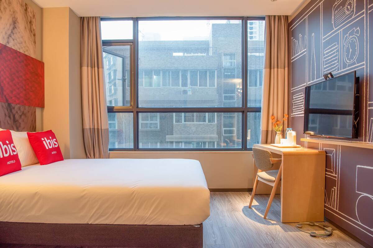 Ein Hotelzimmer mit einem großen Bett, einem Schreibtisch und einem Fernseher.