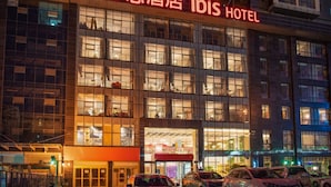 A hotel building with illuminated signage for "Ibis Hotel".