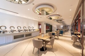 A modern restaurant with round mirrors on the wall, a counter with food items, and several tables and chairs. - Jinjiang Inn Guangzhou Haizhu Jiangyan Road (Guangzhou)