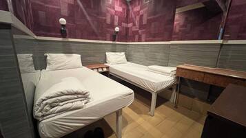 Una habitación de hotel con dos camas, una mesita y un banco.