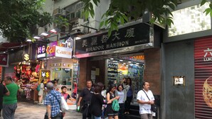 A busy street with various shops and pedestrians. - USA Hostel (Kowloon)