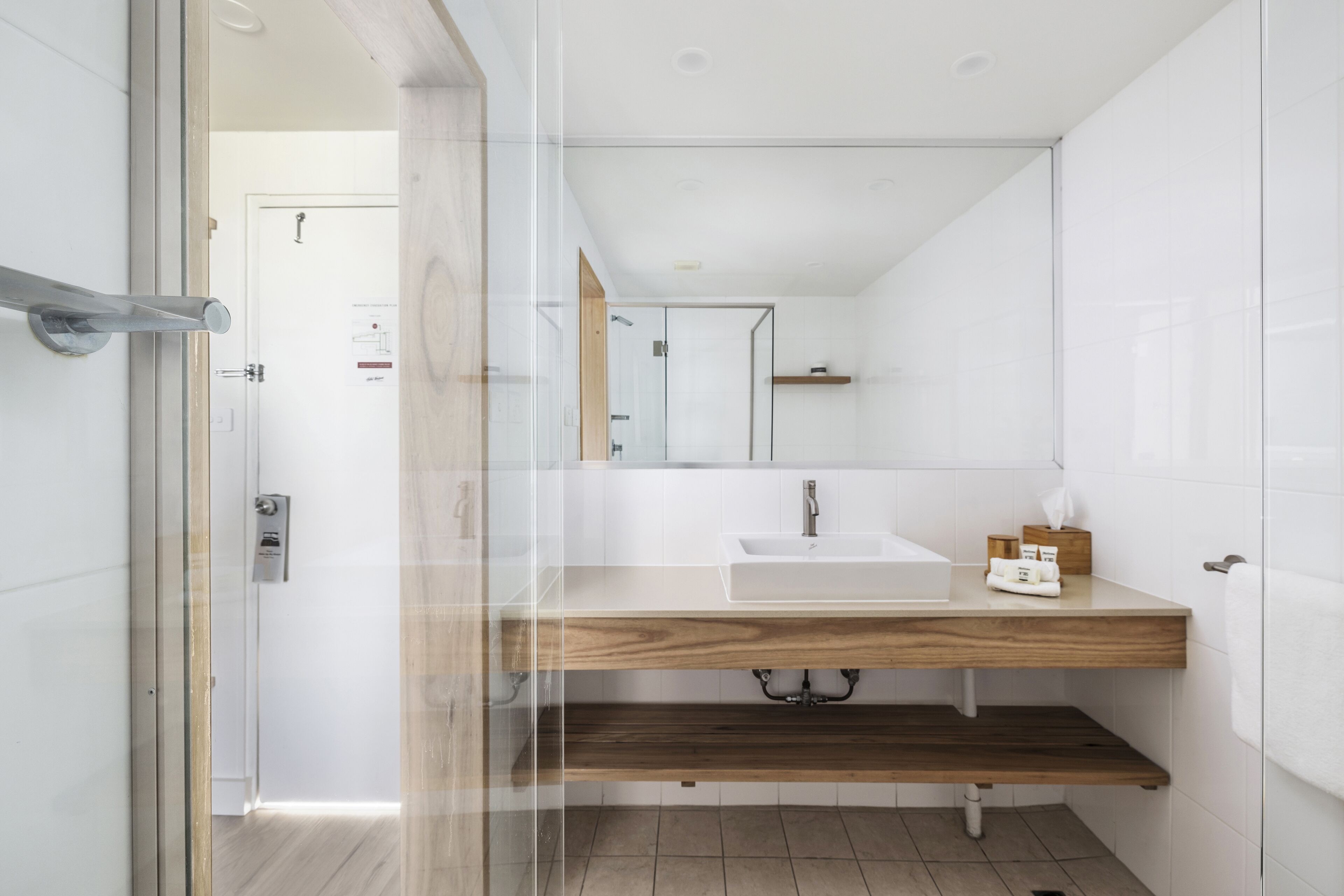 A modern bathroom with a glass shower enclosure, a wooden vanity, and a white sink.