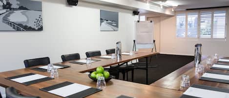 A conference room with a long table, chairs, a projector, and artwork on the walls.