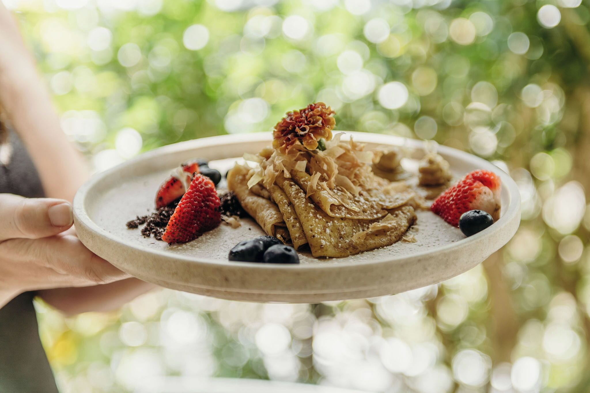 A plate with pancakes, strawberries, and blueberries.