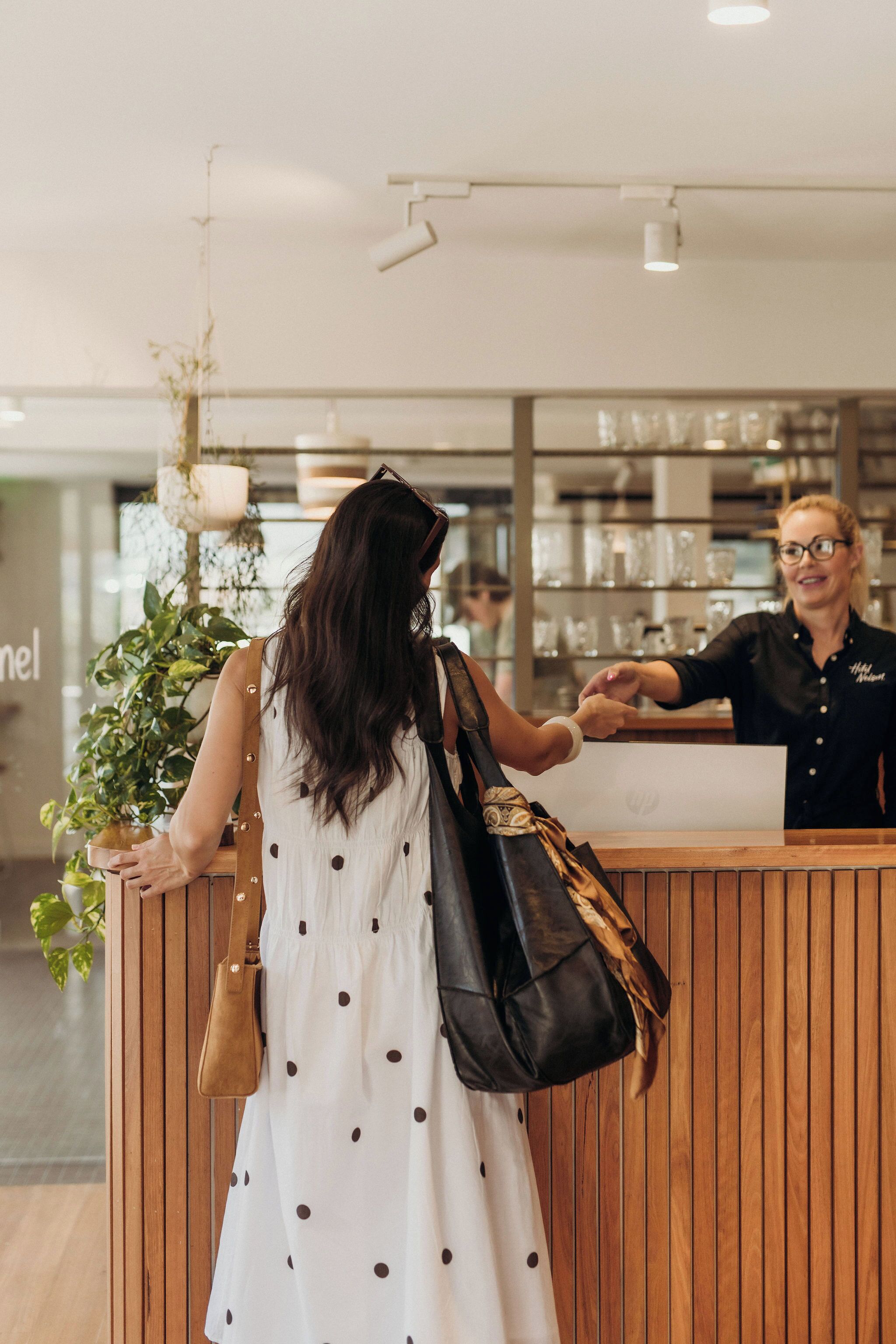 A reception area with a wooden counter, a potted plant, and a person standing behind the counter.