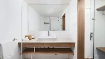 A modern bathroom with a white sink, wooden vanity, and a glass shower enclosure.