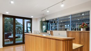 A reception desk with a laptop, wooden paneling, and a glass display case with items. - Hotel Nelson (Nelson Bay)