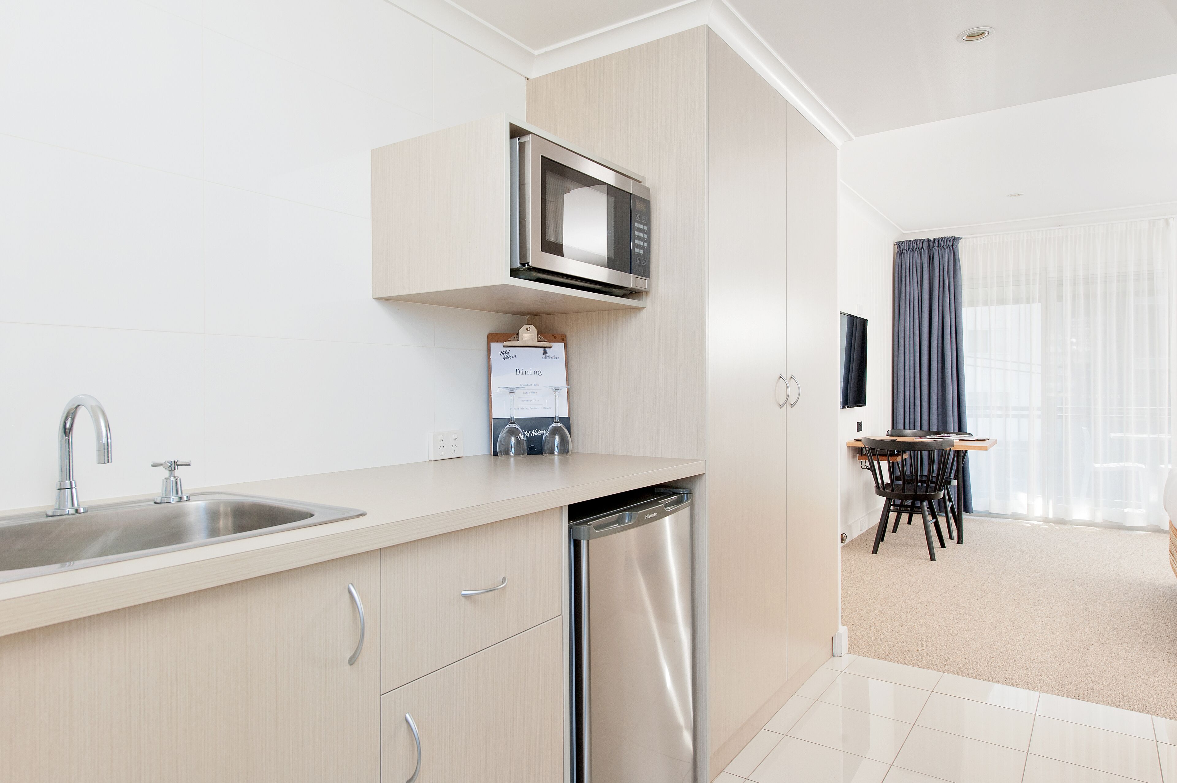 Una cucina moderna dotata di microonde integrato, lavastoviglie e zona pranzo con tavolo e sedie.