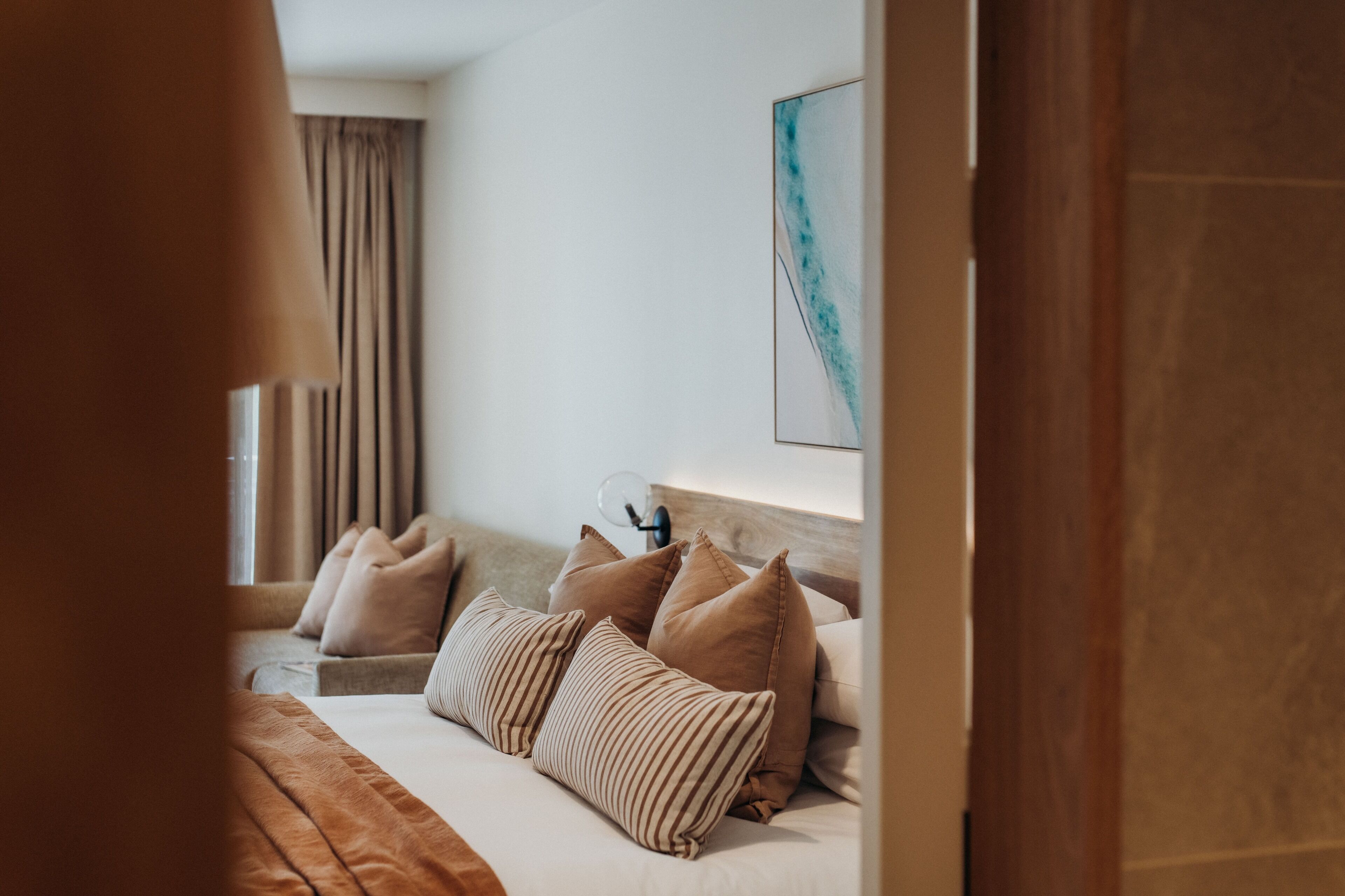 Una habitación de hotel con una cama, un sofá y un televisor montado en la pared.