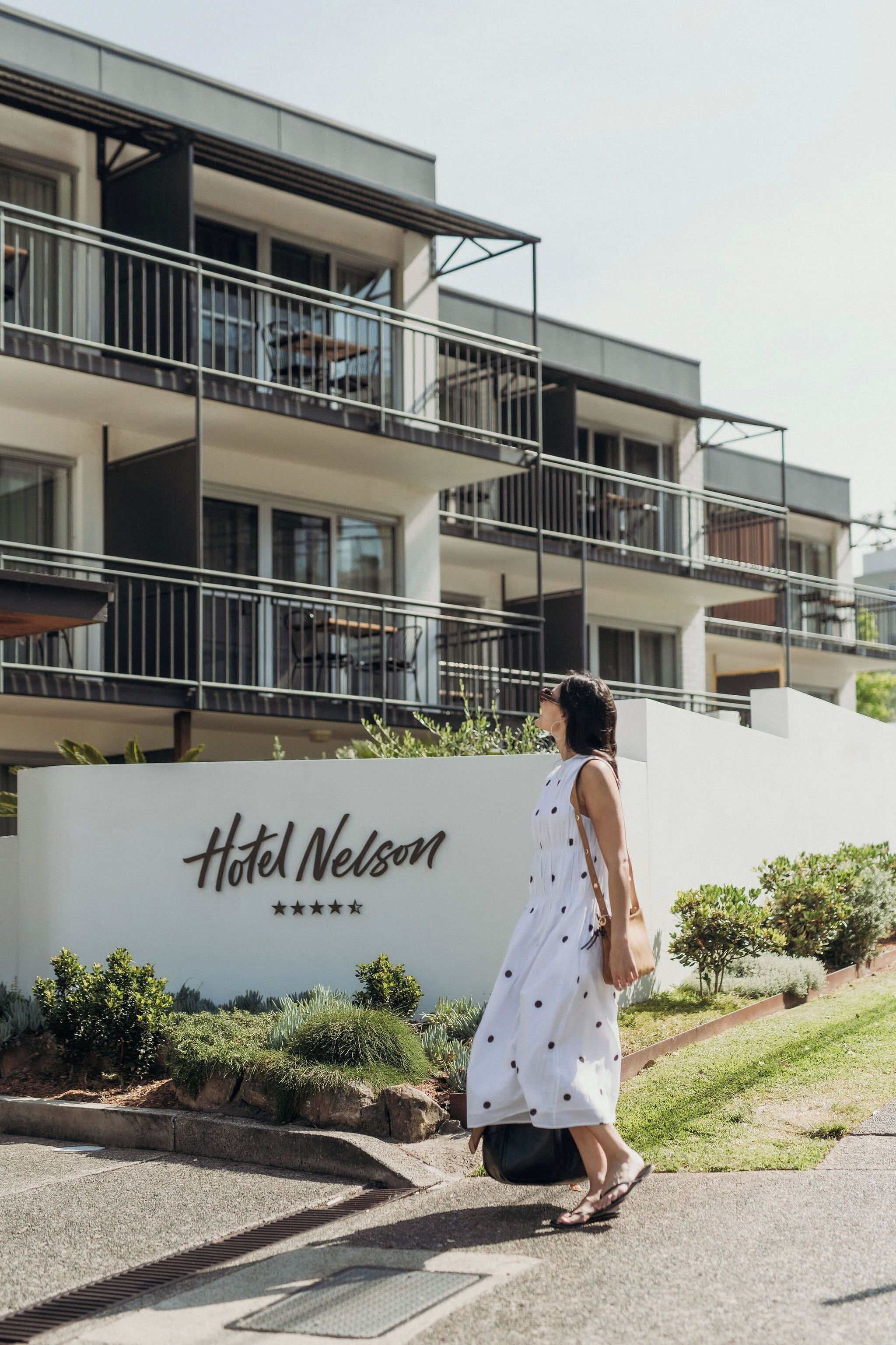 Una mujer caminando frente a un edificio con un letrero que dice "Hotel Nelson".