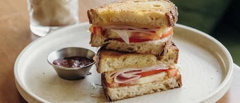 A sandwich on a plate with a drink in the background.