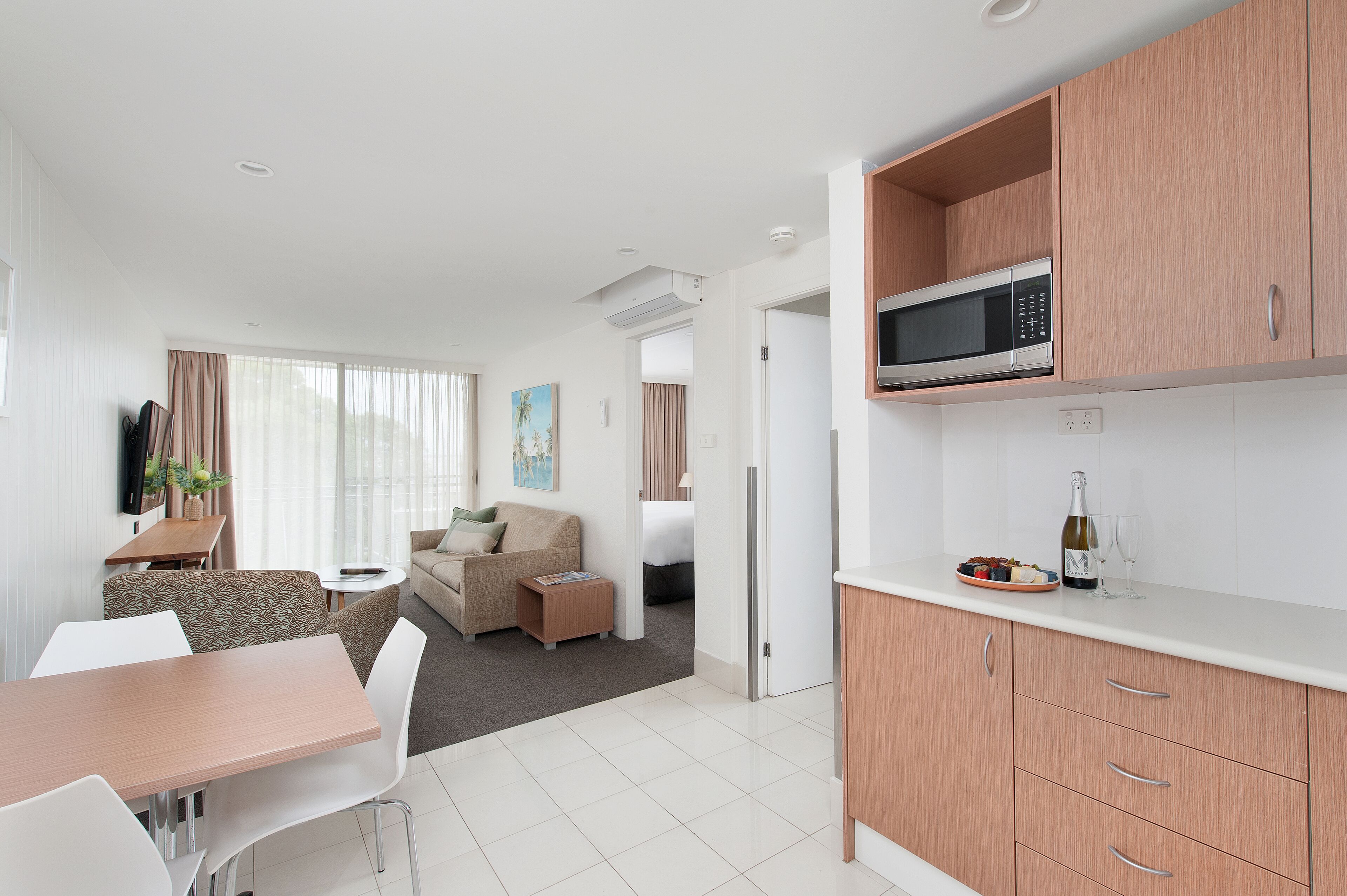 A modern kitchen with a microwave, a dining area with a table and chairs, a sofa, and a small side table.