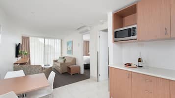 A modern kitchen with a microwave, a dining area with a table and chairs, a sofa, and a small side table.
