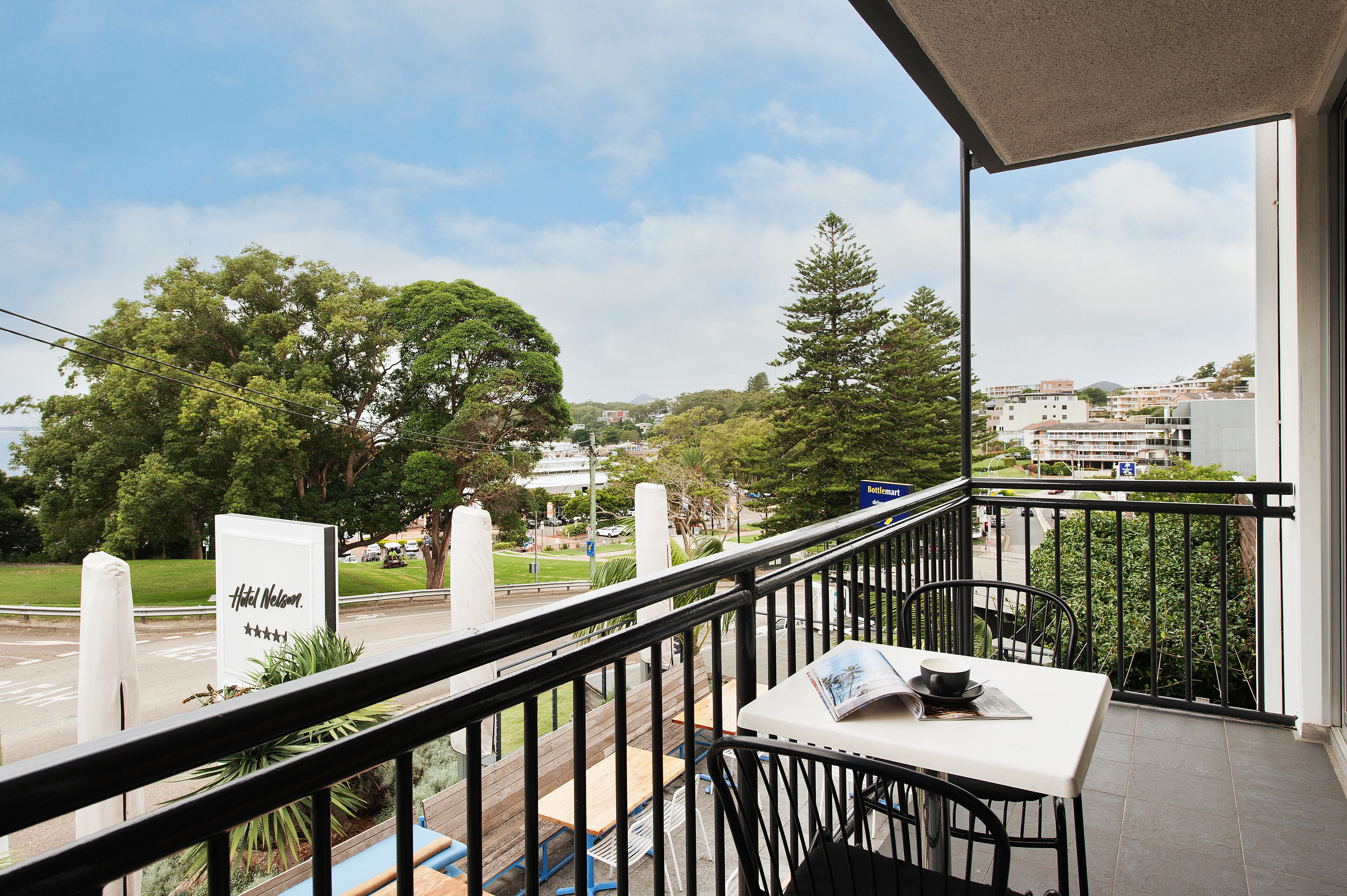 A balcony with a view of a hotel sign, a table with a menu, and a railing.