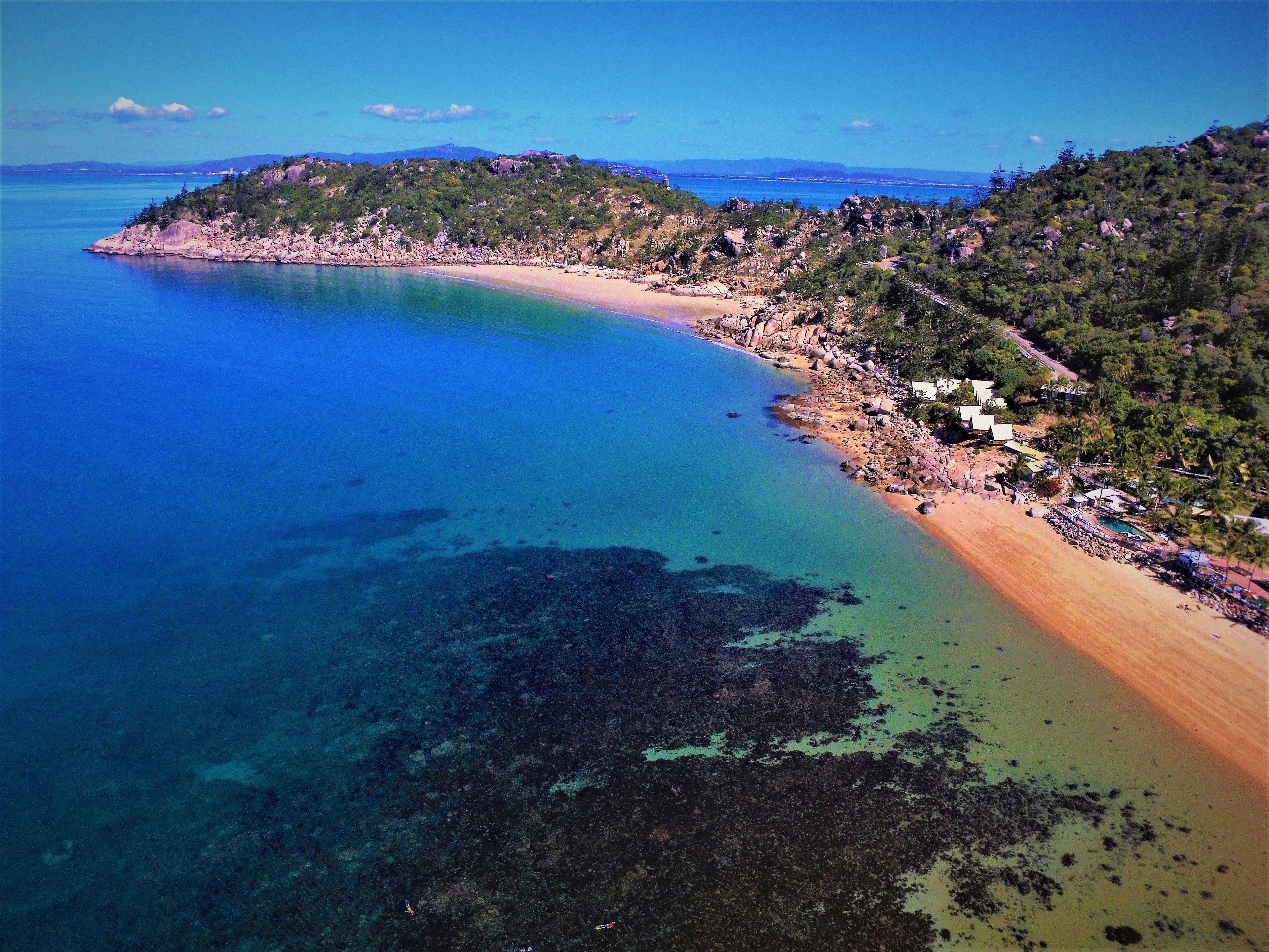 A coastal area with a beach, rocky terrain, and a clear blue sea.
