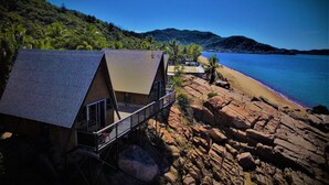 Alojamiento frente a la playa con estructura de madera, terraza y vistas al mar y a las montañas.