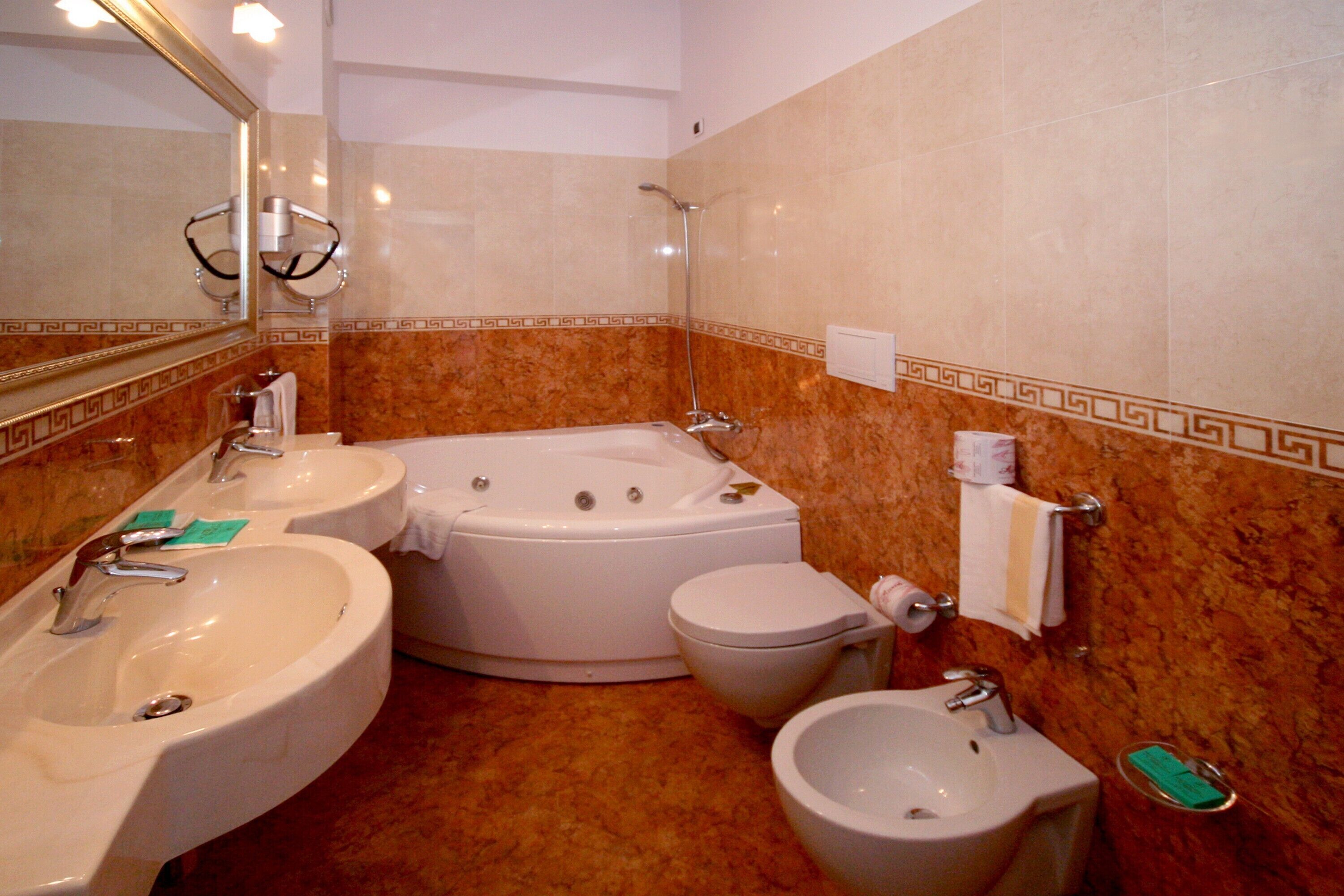 A bathroom with a bathtub, two sinks, a toilet, and a bidet.