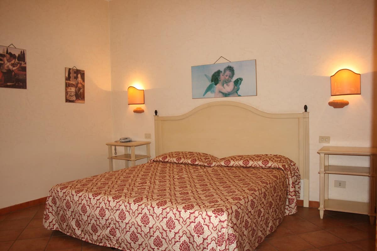 Un dormitorio con una cama, dos mesitas de noche y lámparas fijadas a la pared.
