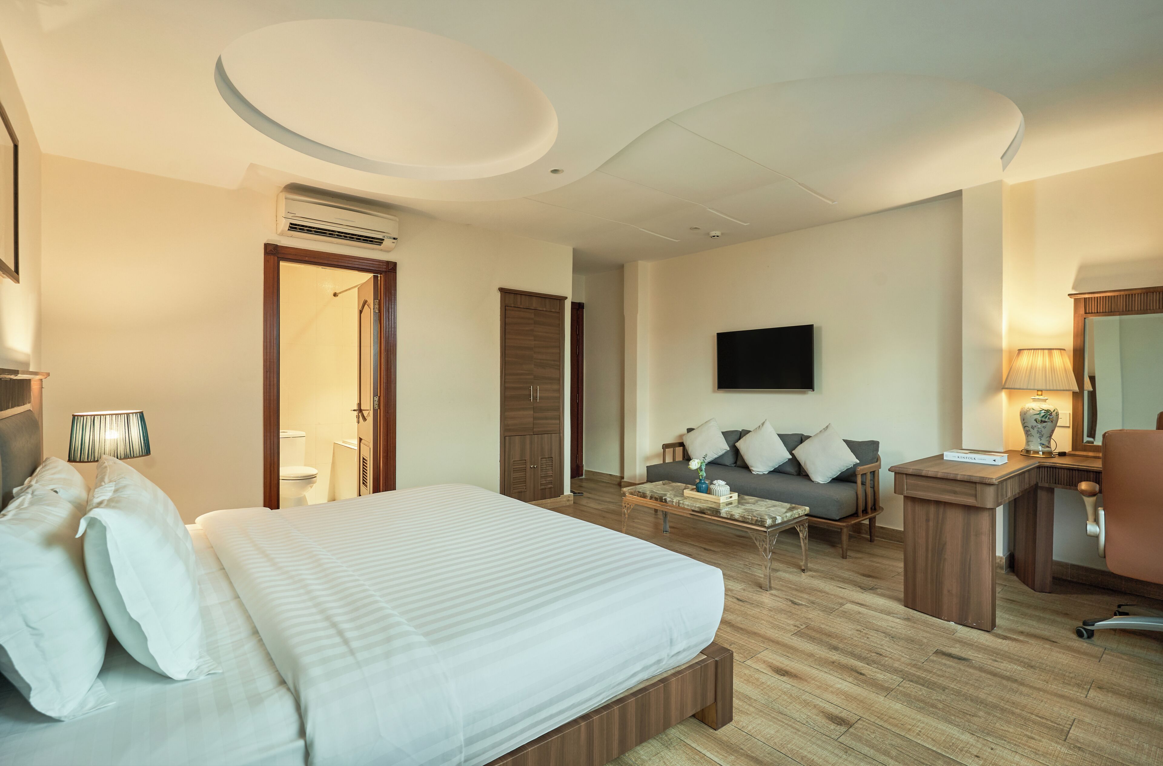 A hotel room with a bed, a sofa, a desk, and a TV.