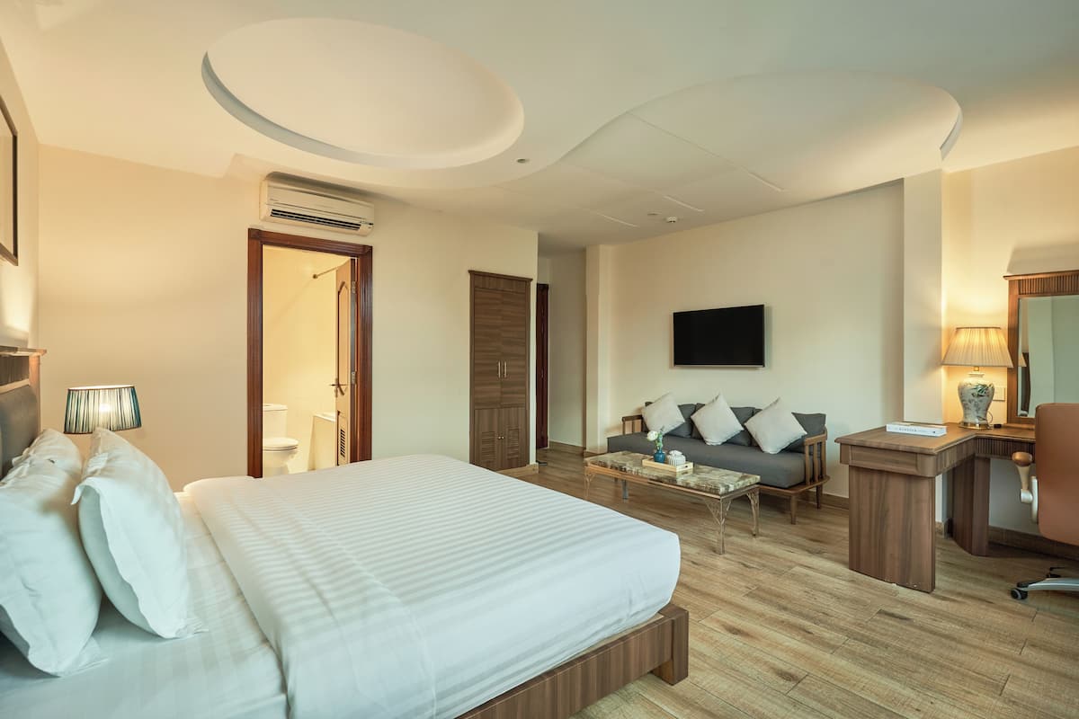 Une chambre d’hôtel avec un lit, un canapé, un bureau et une télévision.