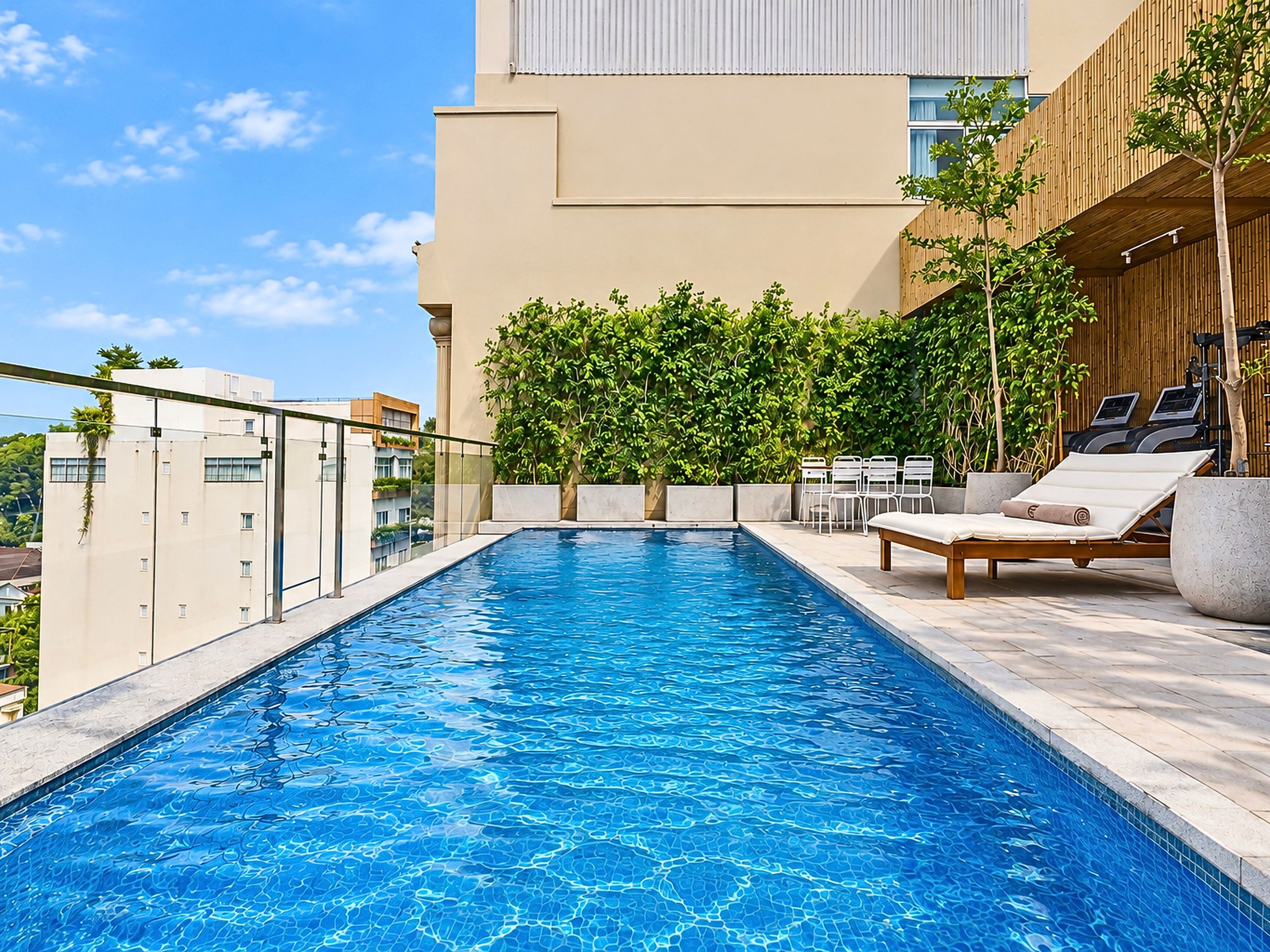 A rooftop swimming pool with a clear blue water surface, surrounded by a wooden deck and lounge chairs.
