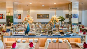 A buffet setup with multiple food stations, a mirror reflecting the room, and a dining area with chairs and tables.